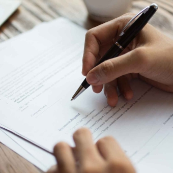Eine Person hält einen Kugelschreiber, um ein Dokument zu unterschreiben