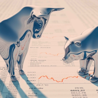 Bulle und Bär Figuren stehen auf einem Zeitungsausschnitt