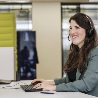 Frau an einem PC lächelt.