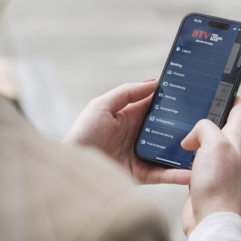 Eine Frau hält ihr Handy in der Hand und schaut in ihr Internetbanking.