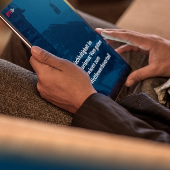 Hände halten ein Tablet in der Hand auf dem zu lesen ist: "Nachhaltigkeit im Tourismus: Vom guten Gewissen zum Wettbewerbsvorteil."